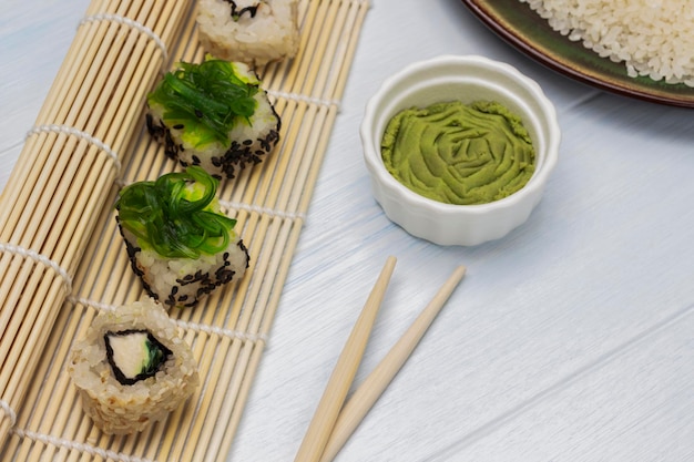 Seaweed sushi set on bamboo sushi mat Wasabi in a bowl Chopsticks on the table