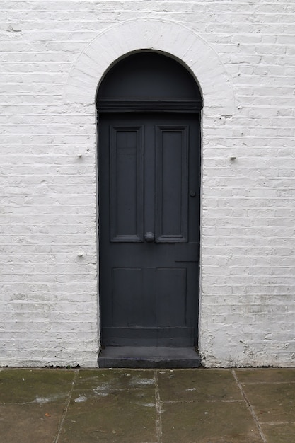 Foto porta nera segreta sul muro di mattoni bianco