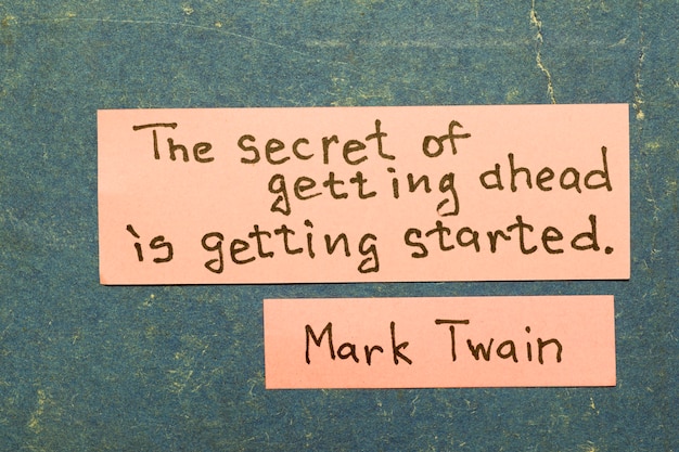 The secret of getting ahead is getting started - famous American writer Mark Twain quote interpretation with pink notes on vintage carton board