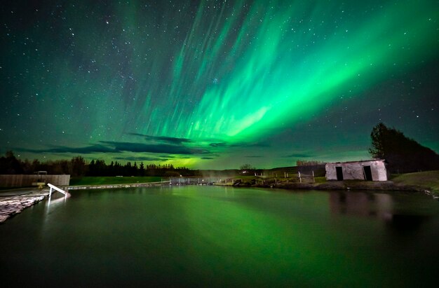 Photo secret lagoon in fluir village in iceland with northern lights reflecting in the pool water