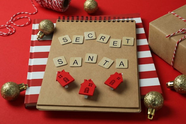 Secret Santa and Christmas composition on red background.