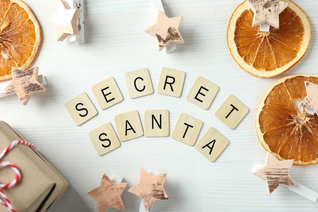 Secret Santa and Christmas composition on white wooden background.