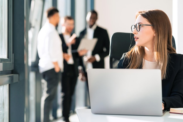 Secretaresse in glazen zit bij laptop