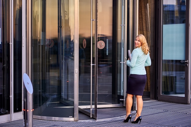 Secretary in business suit stands near revolving door