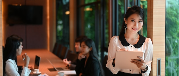 A secretary woman is taking notes while standing over a meeting room