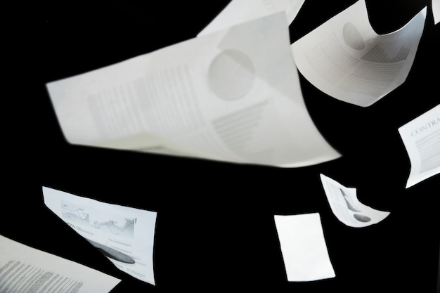 Securities, documents, finances and statistics concept - business papers falling down over black background