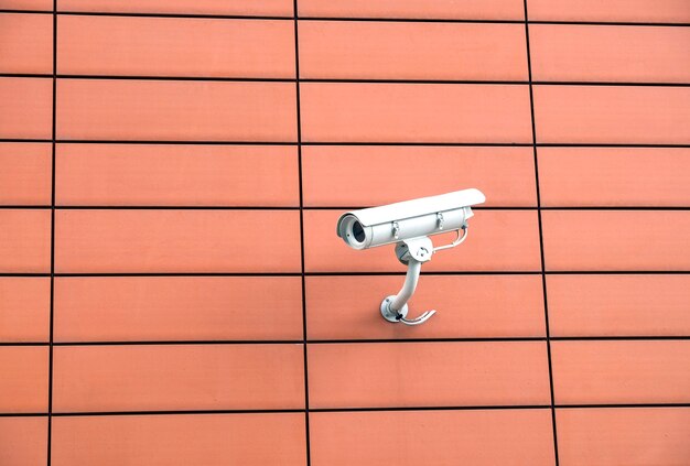 Photo security camera mounted on modern building orange wall horizontal view close up