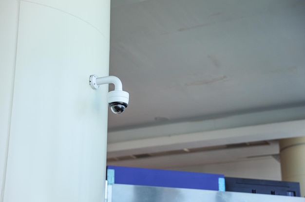 A security camera on a wall with a white background.