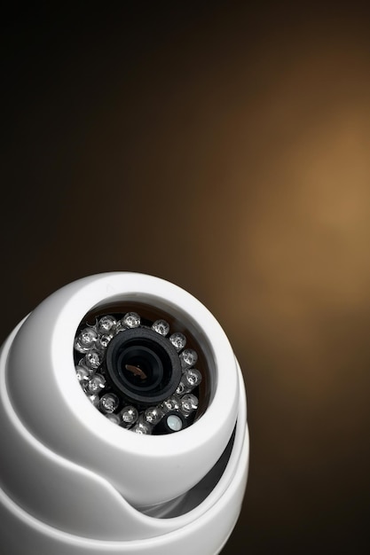 Security CCTV camera on dark yellow background closeup