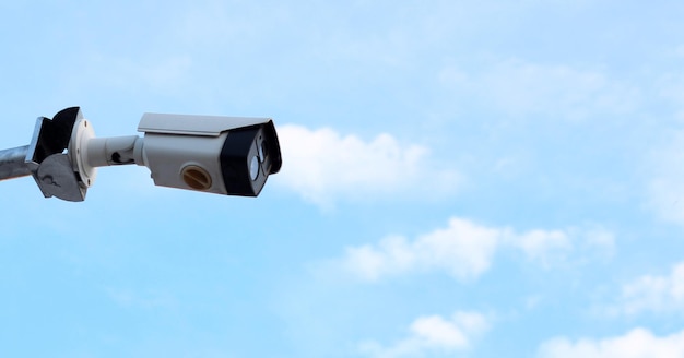 Камера видеонаблюдения на столбе, размытое голубое небо