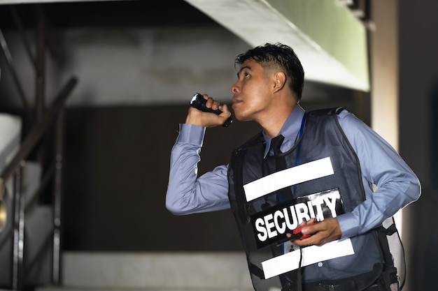 Foto uomo di sicurezza che sta all'aperto con la torcia elettrica in costruzione