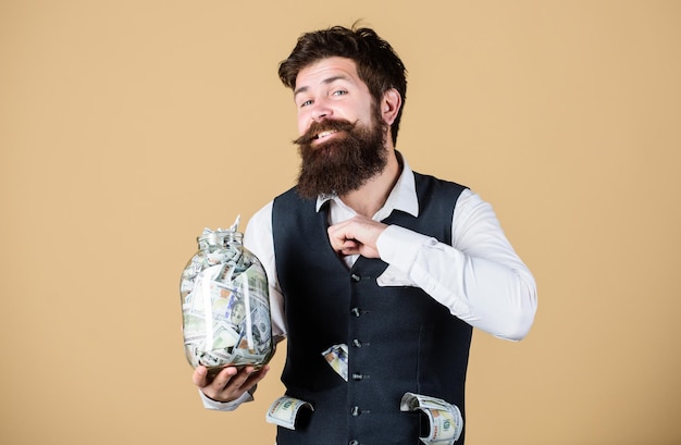 Security and money savings Banking concept Man bearded guy hold jar full of cash savings Safe place to keep money Personal accountant Businessman with his dollar savings Richness and wellbeing