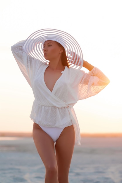 Donna seducente in beachwear sulla riva del tramonto