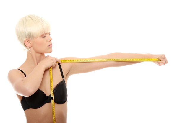 Photo seductive woman wearing bikini holding tape measure while standing against white background