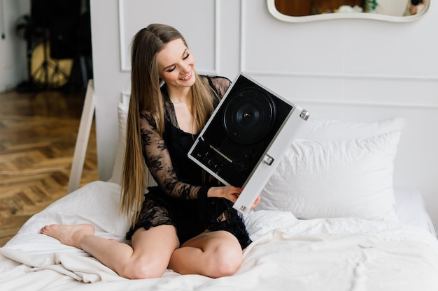 Seductive woman with beautiful long legs listening vinyl at home