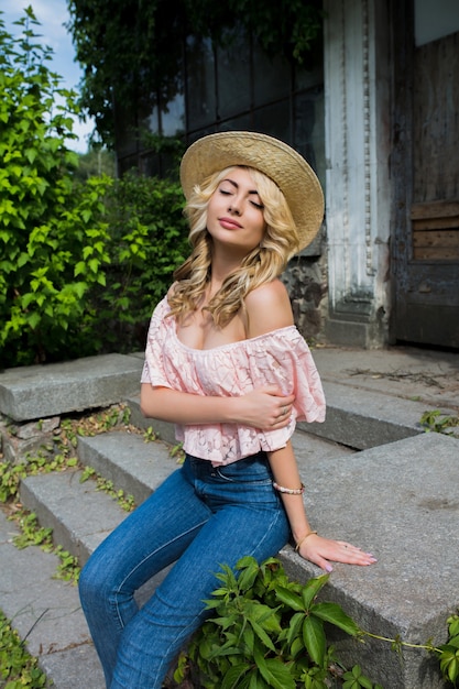 Seductive young model wearing straw hat and lace blouse with naked shoulders