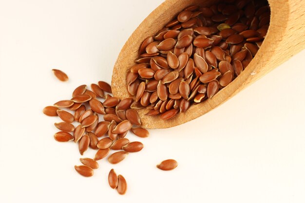 Seed of flax in a scoop on a white surface close-up