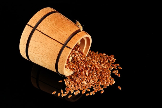 Seeds of flax in a barrel on a black surface