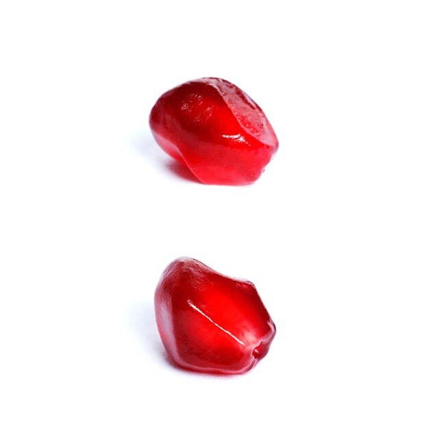 Seeds of a ripe red pomegranate closeup isolated on white background.