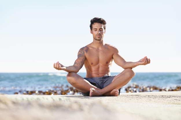 В поисках просветления в природе Молодой человек медитирует рядом с океаном