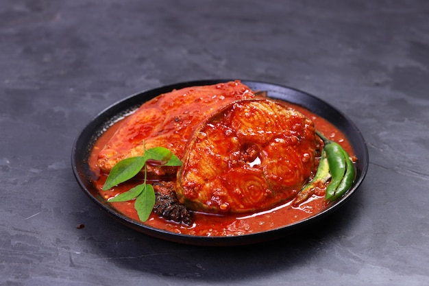 Seer Fish curry  Indian fish curry  arranged in a black bowl garnished with malabar tamarind