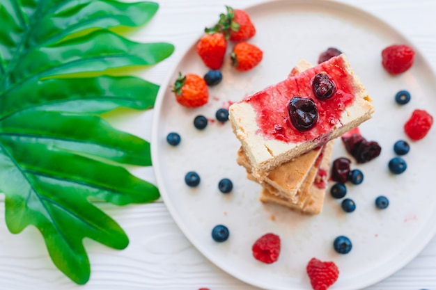Segment van klassieke cheesecake met verse bessen op de witte plaat - gezonde biologische zomer dessert.