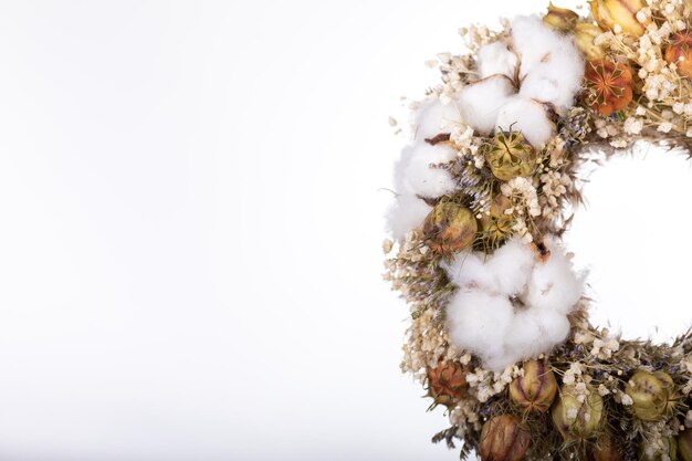 segment of wreath and dried flowers with cotton on white background