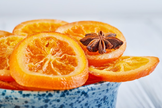 Segmenten van gedroogde sinaasappelen of mandarijnen met anijs en kaneel in een blauwe kom. Vegetarisme en gezond eten