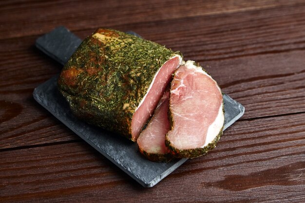 Segmenten van gerky varkensvlees met kruiden en verse groene tijm op leisteen snijplank op houten tafel