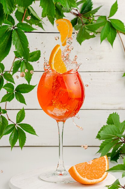 Segmenten van oranje vallen in spatten aperol cocktail.