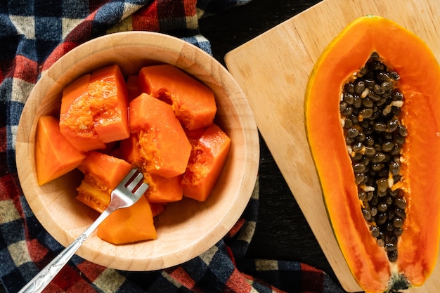 Foto segmenten van zoete papaya in houten kom op zwarte tafel