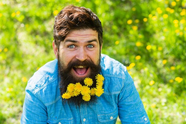 Seizoen van de zomer en lente paardebloem kapper en kapper Floral mode en schoonheid bebaarde hipster genieten van zonnige dag gelukkig man met bloem in baard haar kaalheid en haaruitval concept