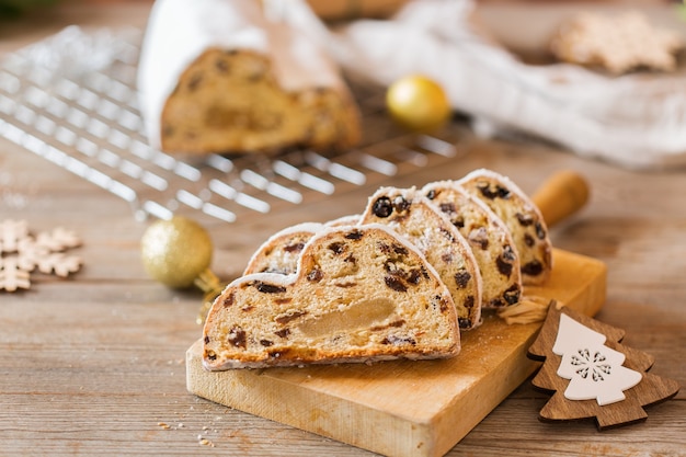 Seizoensgebonden eten en drinken, winterconcept. Traditionele Europese Duitse zelfgemaakte kerstcake, gebakdessert Stollen op een houten ondergrond met feestelijke decoratie.