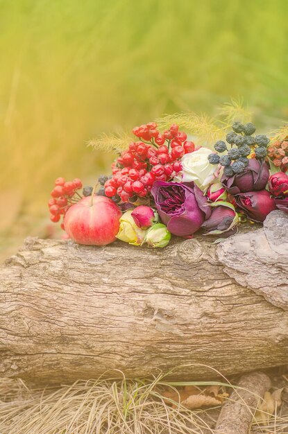 Seizoensgebonden herfststilleven met bloemen fruit, bessen en gebladerte herfst natuur appels en bloemen op de houten achtergrond