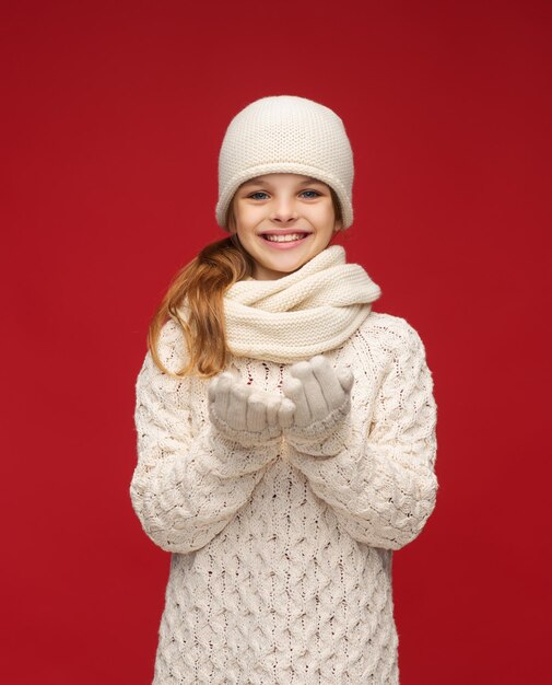 seizoensgebonden, mensen, geluk concept - lachend meisje in winterkleren met iets op handpalmen