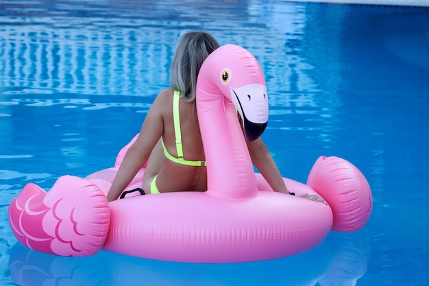 Seizoensrecreatie van een vrouw in het zwembad met een flamingospeeltje