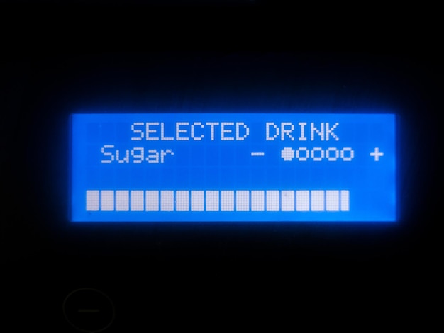 コーヒーマシンの青いディスプレイの選択された飲み物の碑文とロードインジケーターのクローズアップ