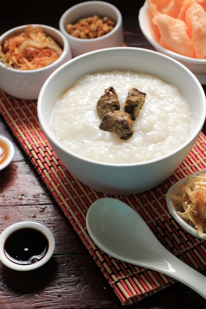 Selected Focus Bubur Ayam or Indonesian Rice  Porridge with Shredded Chicken. Served with Kerukpuk (Cracker), Soy Sauce, Fried Soy Bean, and Sambal