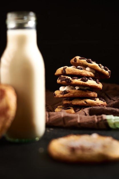 Selected focus, closeup of chocolate chip cookies with milk on a black background.