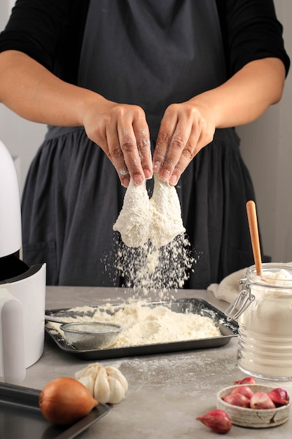 selected focus on drumstick, female home chef making homemade crispy fried chicken, coating chicken drunsticks with flour in the kitchen, action photography