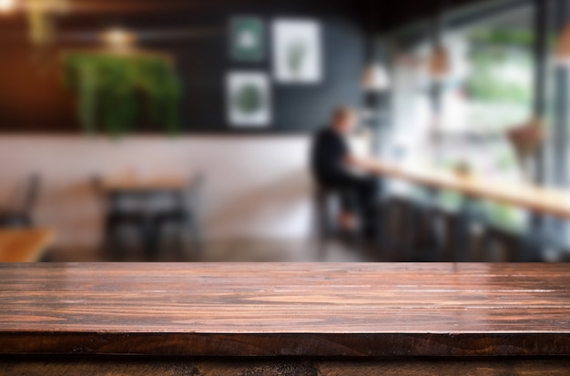 Messa a fuoco selezionata vuota tavolo di legno marrone e coffee shop o ristorante sfocatura sfondo con immagine bokeh. per il tuo fotomontaggio o per il prodotto.