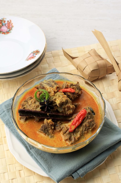 Selected Focus Gulai Sapi is Beef Curry, typisch traditioneel eten uit Padang, West Sumatera, Indonesië. Geserveerd aan tafel met Bowl en Ketupat Lebaran. Menu voor Eid al Adha (Idul Adha)