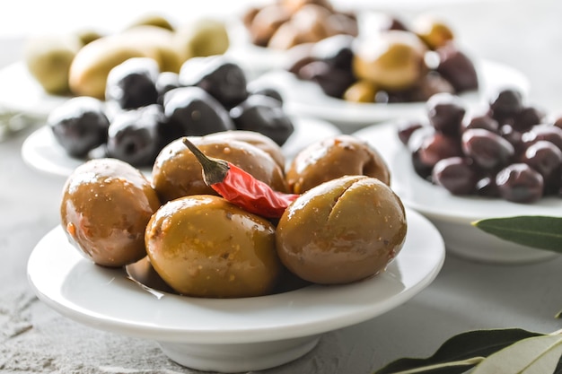 selected olives of different sizes and colors in a ceramic bowl on a concrete background