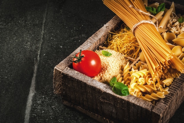 Selectie van verschillende rauwe Italiaanse pasta met basilicum en cherrytomaat