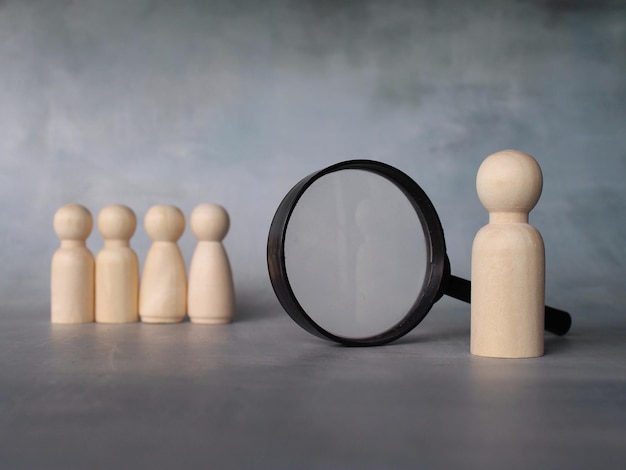 Selectief focusbeeld van vergrootglas en houten poppen met kopieerruimte Bedrijfsrekruteringsinspectie en zoekconcept
