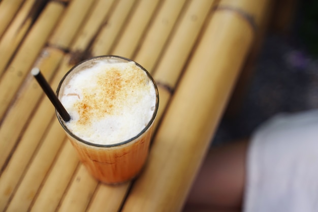 Selectieve aandacht een glas thaise oranje melkthee met het gieten van verse melk die thee en melklaag op aardachtergrond maakt.