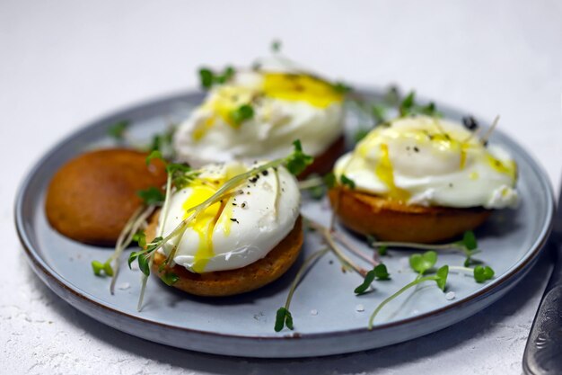 Selectieve aandacht. Gepocheerde eieren op broodjes met microgreens op een bord.