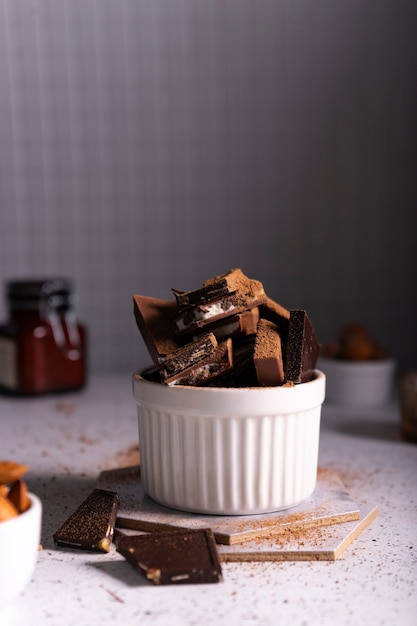 Selectieve aandacht. stukjes melk en bittere chocolade in een keramische witte kop op een lichte achtergrond