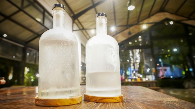 Selectieve focus Een heldere glazen fles gevuld met koud water Een heldere glasfles bevat koud mineraalwater Zit op een houten tafel Water gebruikt om dorst te stillen