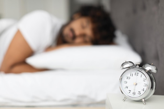 Selectieve focus op alarm op bed boven slapende man